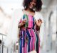Fashionable african american woman in pink striped jumpsuit with Fashionable african american woman in pink striped jumpsuit with fluffy faux fur coat posed at street of megapolis.